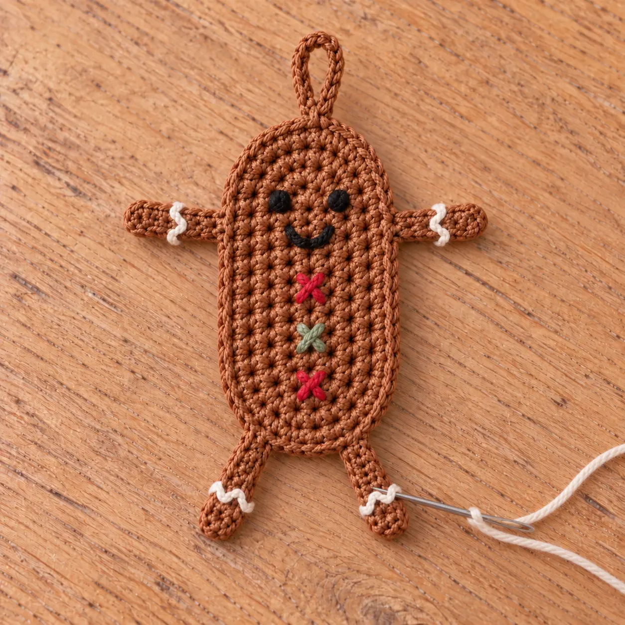 crocheter le bonbonhomme en pain d’épices fini et broder le visage, les boutons et les lignes de glaçage blanc
