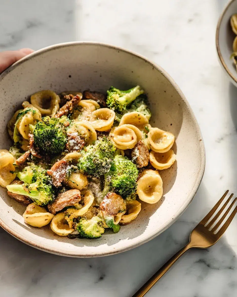 Bowl of orecchiette with sausage and broccoli topped with cheese