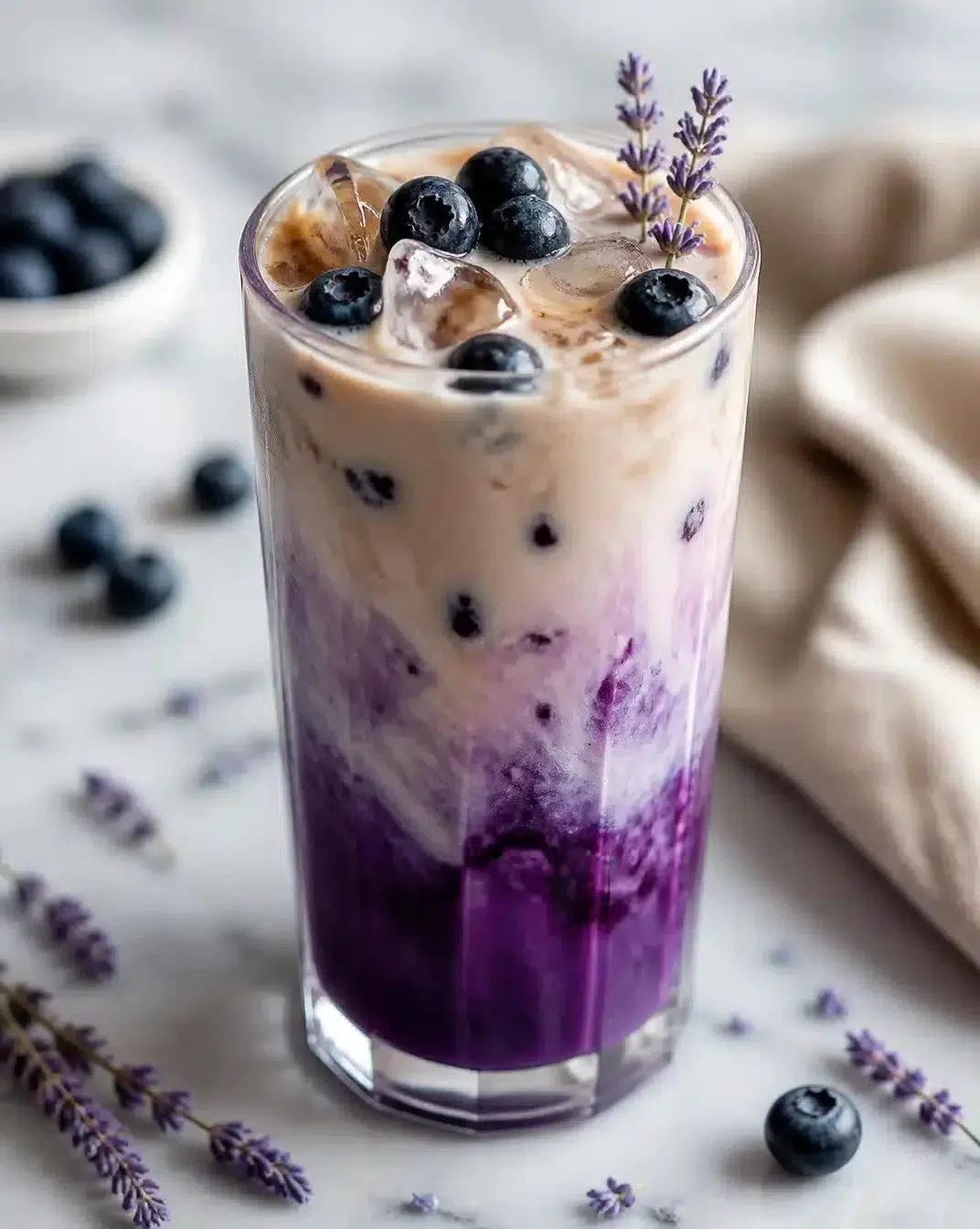 Delicious oat milk latte topped with blueberry and lavender flowers.