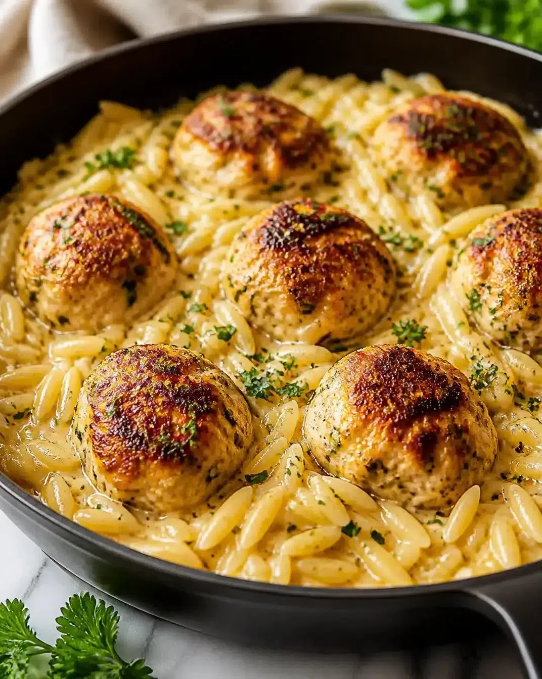 Skillet chicken meatballs served with orzo in a delicious sauce.